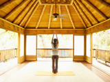 Photo: Rear view of woman standing with arms raised inside yoga and meditation pagoda at a luxury resort Rear view of woman standing with arms raised inside yoga and meditation pagoda at a luxury resort