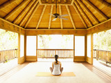 Photo: Rear view of woman sitting in lotus position on floor of yoga and meditation pagoda at a luxury resort Rear view of woman sitting in lotus position on floor of yoga and meditation pagoda at a luxury resort