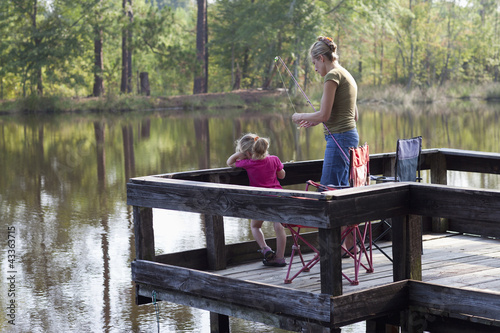 Photo: Caucasian mother fishing on pier with daughter Caucasian mother fishing on pier with daughter