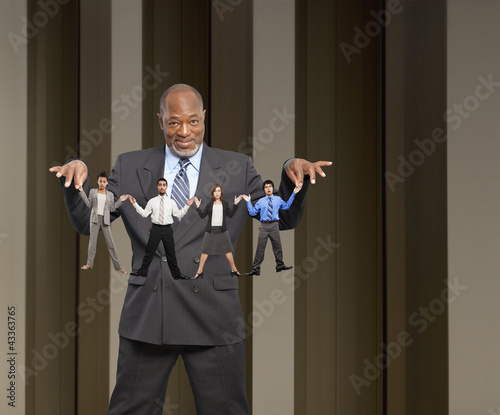 Photo: African American businessman holding string of small business people African American businessman holding string of small business people