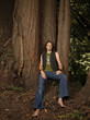 Barefoot Caucasian man leaning against tree trunk