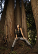 Woman leaning against tree trunk in forest