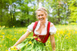 Junge Frau in traditionellem Dirndl auf einer Frühlingswiese