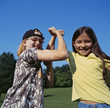 Smiling girls flexing biceps outdoors