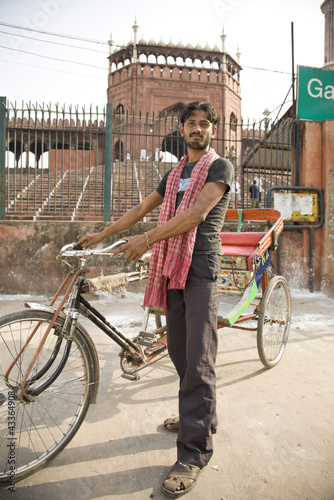 Photo: Mixed race man standing with bicycle taxi Mixed race man standing with bicycle taxi
