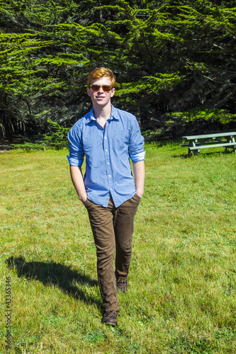 Photo: teenage boy with sunglasses walks happy on the meadow teenage boy with sunglasses walks happy on the meadow