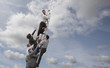 Business people chasing co-worker up ladder into clouds