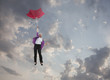 Caucasian businesswoman holding umbrella and falling through clouds