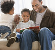 African American father reading book to sons