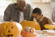 Grandfather and grandson carving a pumpkin