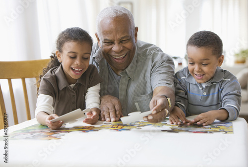Photo: Grandfather and grandchildren putting a puzzle together Grandfather and grandchildren putting a puzzle together