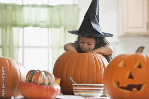 Photo: Hispanic girl in witch's hat carving a pumpkin Hispanic girl in witch's hat carving a pumpkin
