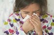 Mixed race girl blowing nose