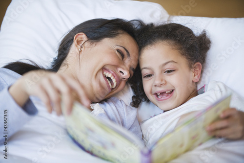 Photo: Hispanic mother reading book to daughter Hispanic mother reading book to daughter