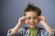 Caucasian boy putting on eyeglasses