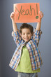 Caucasian boy holding up sign that says 'yeah!'