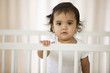 Hispanic baby girl standing in crib