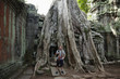 Caucasian man standing by large tree roots in ruins