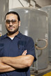 Hispanic worker in factory with arms crossed