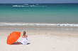 Foto: Girl with an orange umbrella on the sandy beach Girl with an orange umbrella on the sandy beach
