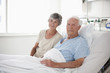 Wife sitting with husband in hospital bed