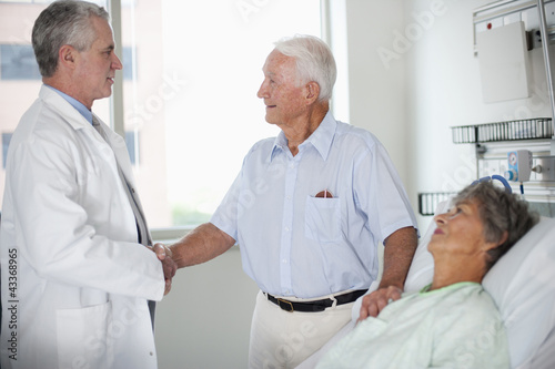 Photo: Doctor talking to patient's husband in hospital room Doctor talking to patient's husband in hospital room