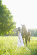 Hispanic woman standing with horse in pasture