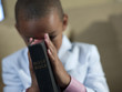 Mixed race boy praying with bible