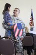 Hispanic soldier holding daughter at political gathering
