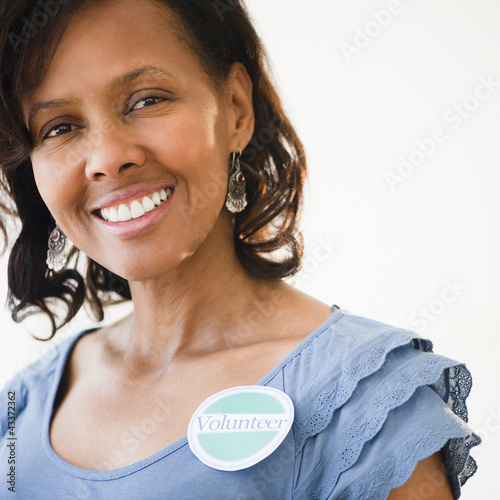 Photo: Black woman wearing volunteer badge Black woman wearing volunteer badge