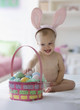 Caucasian baby girl in bunny costume with Easter eggs