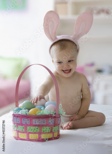 Photo: Caucasian baby girl in bunny costume with Easter eggs Caucasian baby girl in bunny costume with Easter eggs