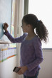 Hispanic girl writing on classroom blackboard