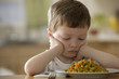 Unhappy Caucasian boy looking at dinner