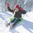 Hispanic girl sledding down snow covered hill