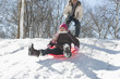 Father watching daughter sledding down snow covered hill