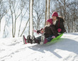 Hispanic girls sledding down snow covered hill
