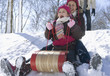 Hispanic girls sledding down snow covered hill