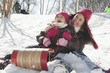 Hispanic girls sledding down snow covered hill