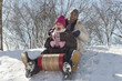 Father and daughter sledding down snow covered hill