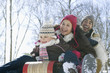 Father and daughters sledding down snow covered hill