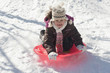 Hispanic girl sledding on snow covered hill