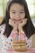 Mixed race girl with pancakes with candles