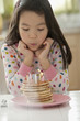 Mixed race girl blowing out candles on pancakes