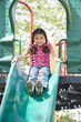 Hispanic girl sliding down slide on playground