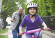 Hispanic grandfather teaching granddaughter to ride bicycle