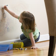 Caucasian girl drawing on wall