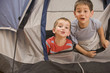 Caucasian brothers looking out of tent