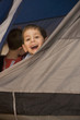 Caucasian boy peering out of tent