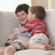 Boy kissing brother on sofa